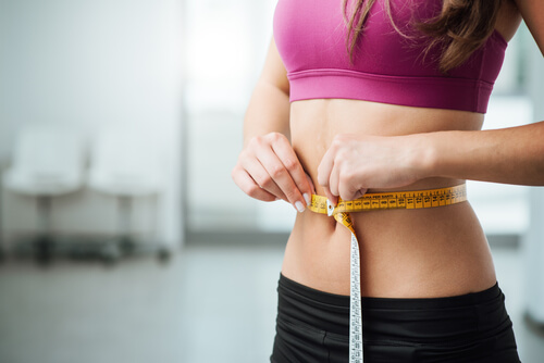 woman holding measuring tape around stomach